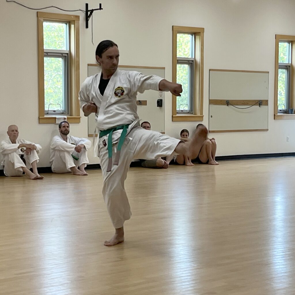 A karate student kicks while striking