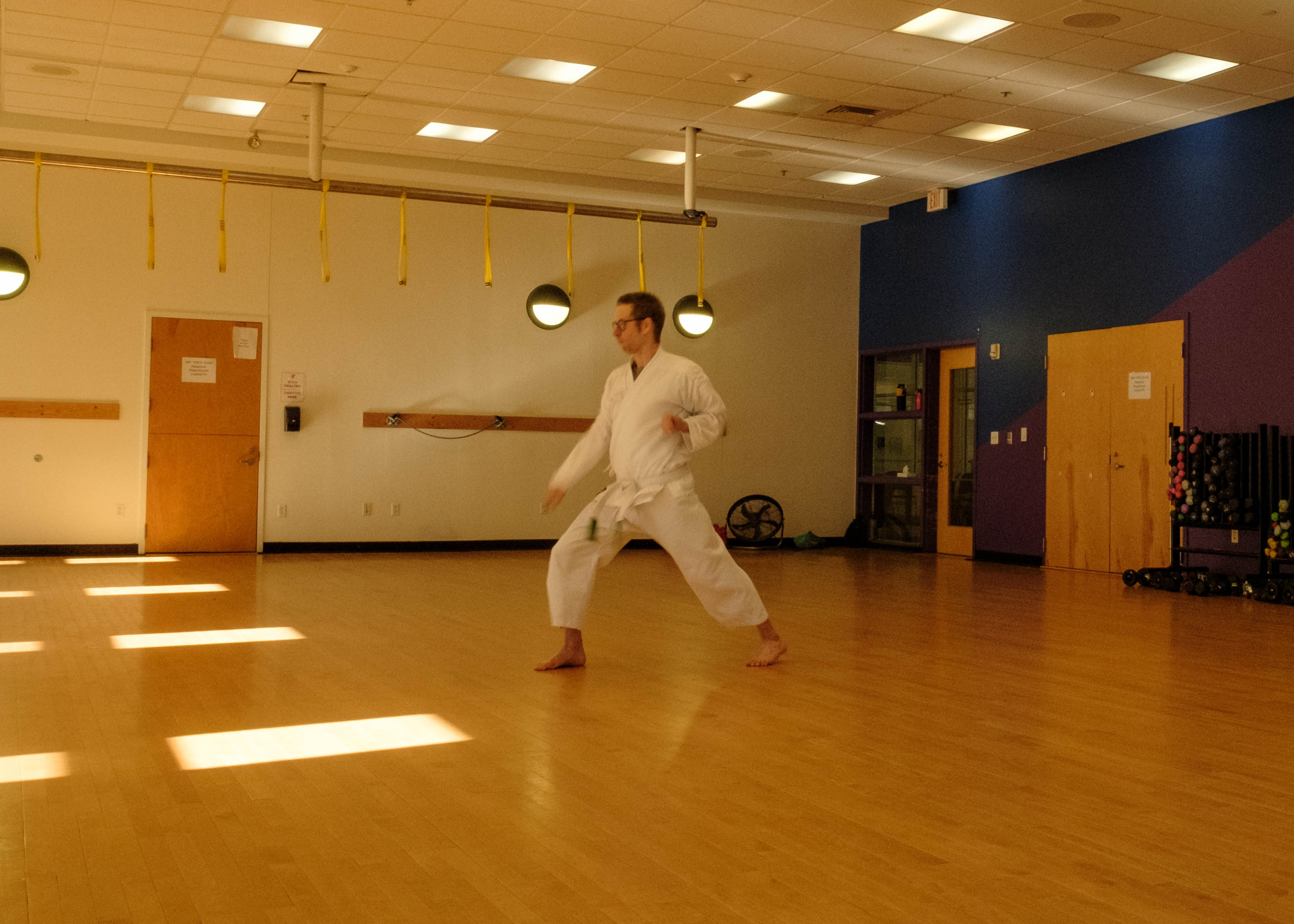 A karate student in white karate gi performs a zenkutsudachi gedan uke