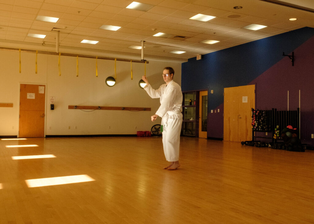 A karate student in white karate gi performs a morote gedan uke