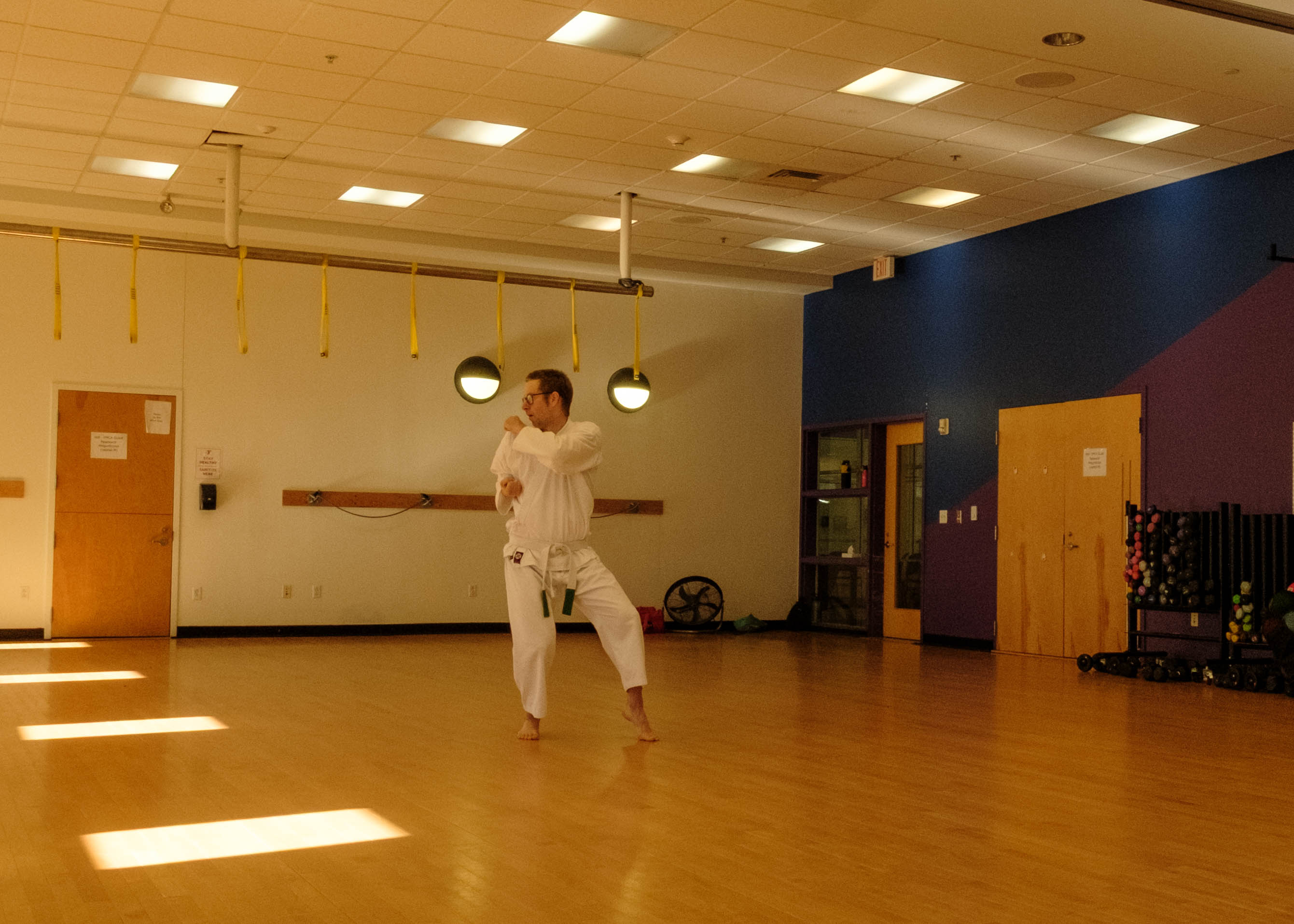 A karate student in white karate gi performs an over the shoulder elbow strike in nekoashi dachi
