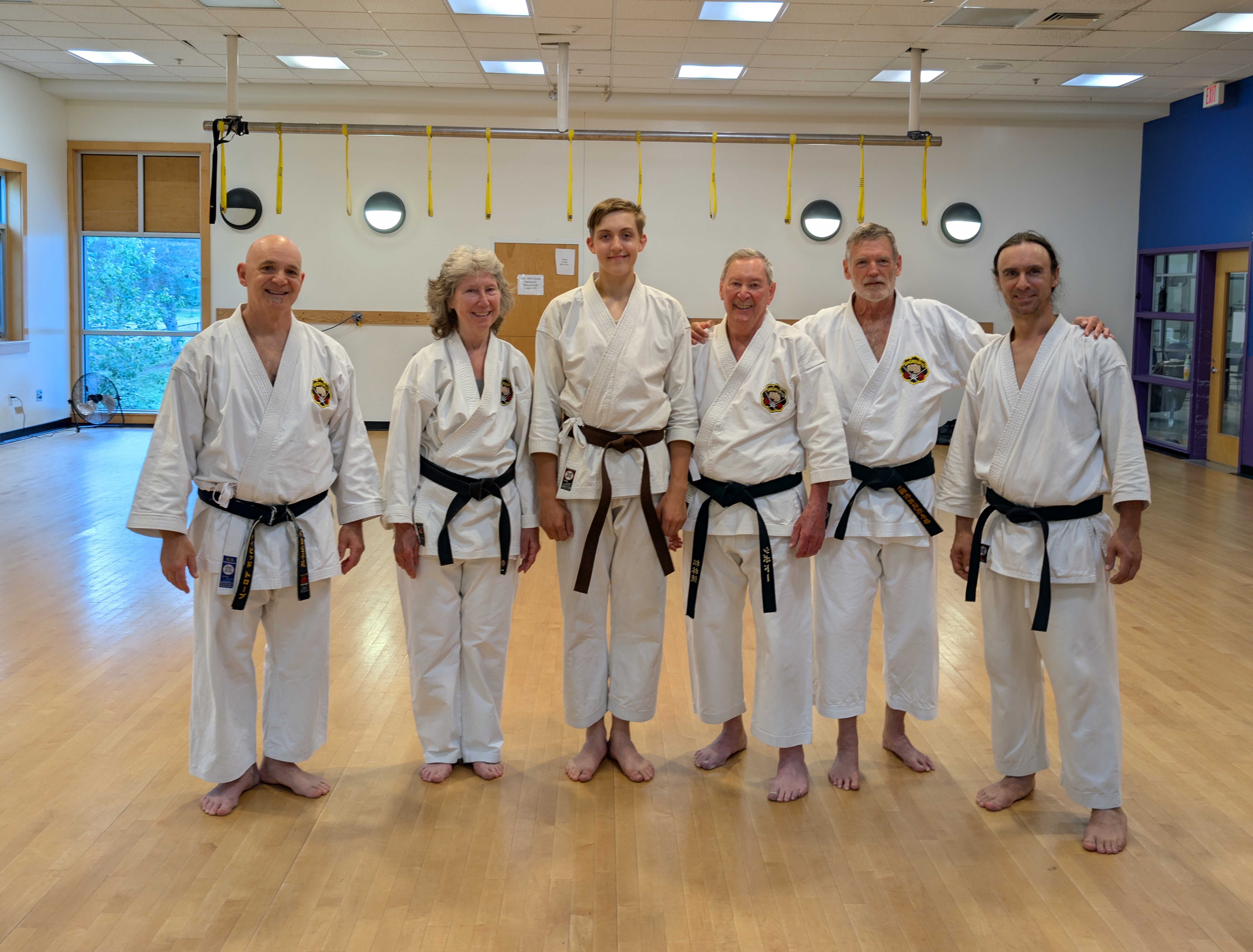 6 Karate students in uniform with the brown belt in the middle